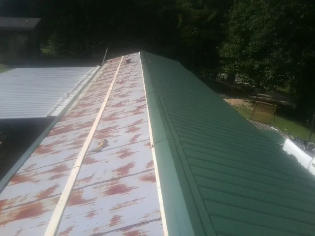 Old rusted panels beside newly installed green metal roofing — Wind Damage Roof Repair by Roofing Brothers in Daufuskie Island
