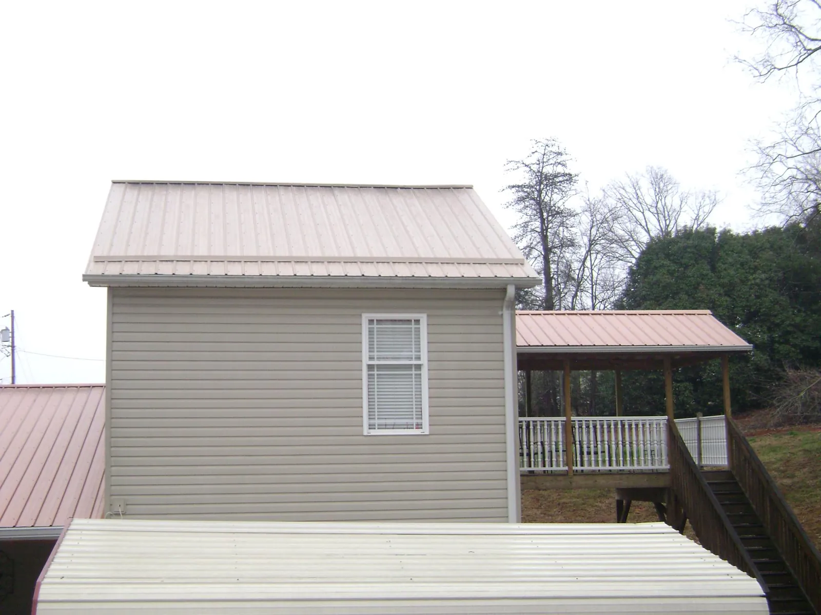 Tan metal roofs on a two story addition and attached porch, from a Roof Replacement job in Daufuskie Island